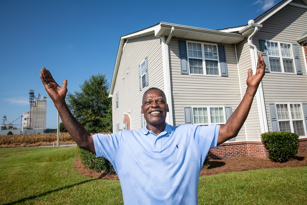 Homme souriant devant sa maison